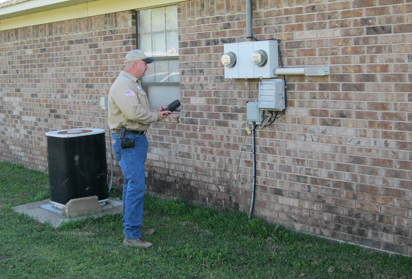 A man reads the meter outside of a brick building
